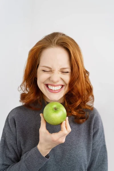 Aufgeregte junge Frau hält einen frischen grünen Apfel in der Hand — Stockfoto