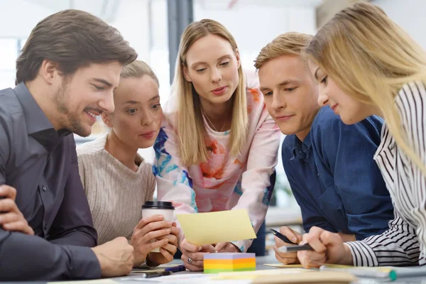 Grupp unga människor att undersöka en handskriven anteckning — Stockfoto