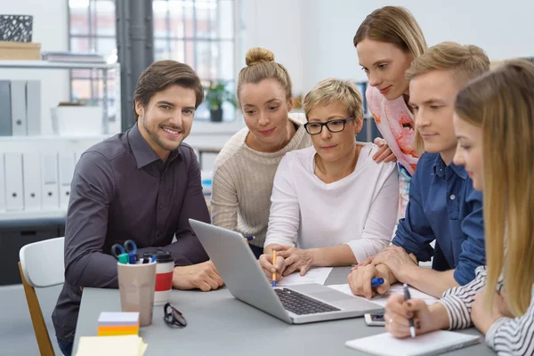 Toegewijde business team gegroepeerd rond een laptop — Stockfoto