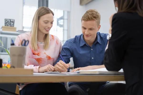 Pareja joven firmando una propuesta de negocio — Foto de Stock