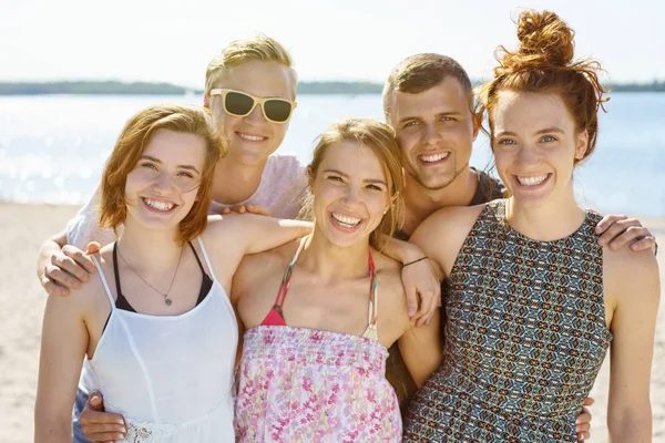 Estudantes posando braço a braço em uma praia — Fotografia de Stock