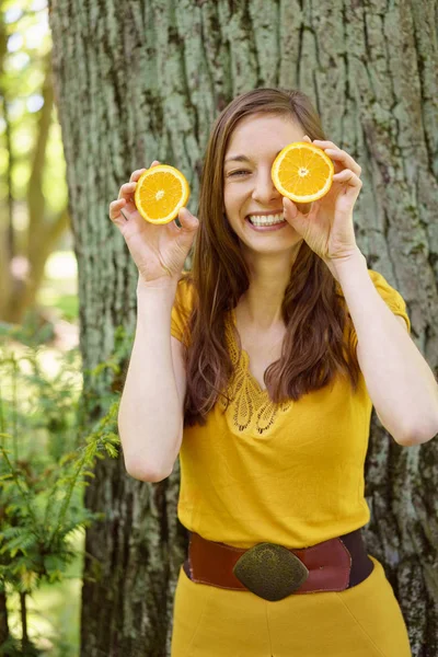 Niedliche temperamentvolle junge Frau mit geschnittenen Orangen — Stockfoto