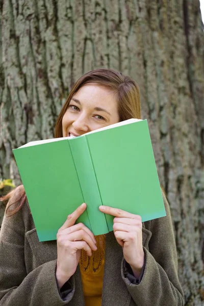 彼女の本の後ろに隠れて恥ずかしそうな若い女性 — ストック写真