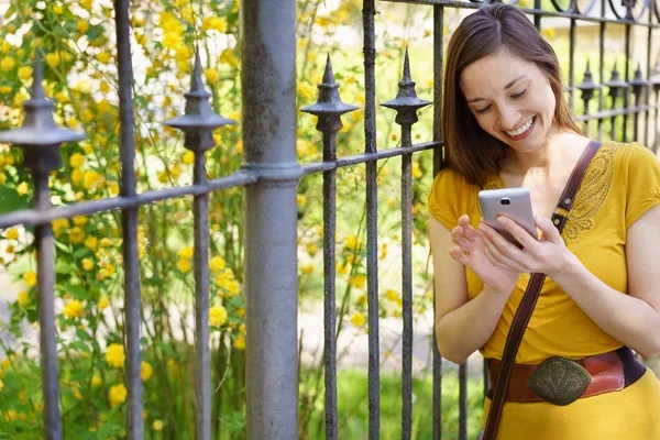 Szczęśliwa młoda kobieta sprawdzania jej telefon komórkowy — Zdjęcie stockowe