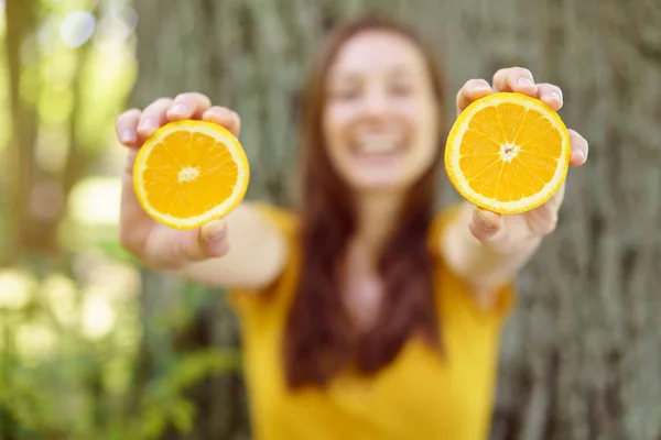 Lachende Frau mit einer geschnittenen Orange — Stockfoto