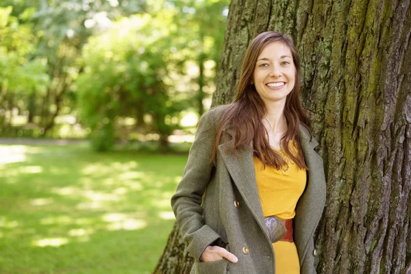 Stylische freundliche junge Frau, die in einem Park spaziert — Stockfoto
