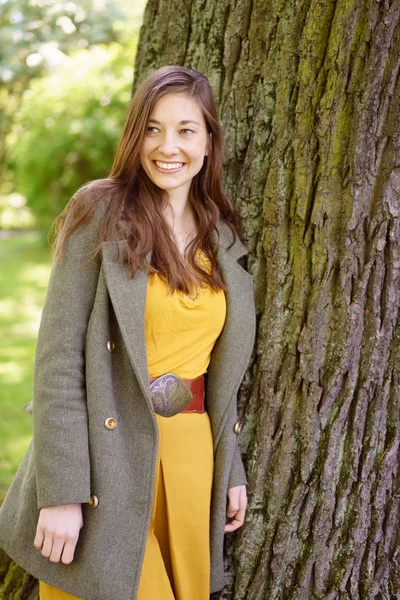 Mujer bonita al lado del tronco del árbol en el parque — Foto de Stock