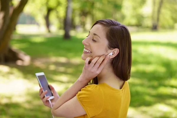 Woman listening to music in the shade of a tree — Stock Photo, Image