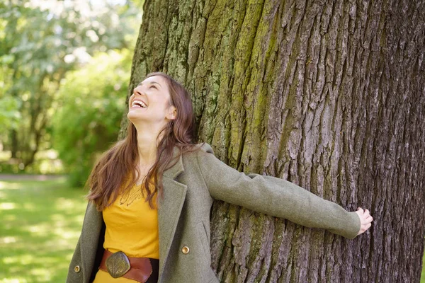Vrolijke jonge vrouw omhelst boom — Stockfoto