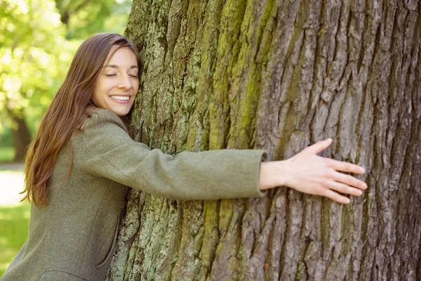 Jonge vrouw stam van de boom knuffelen — Stockfoto