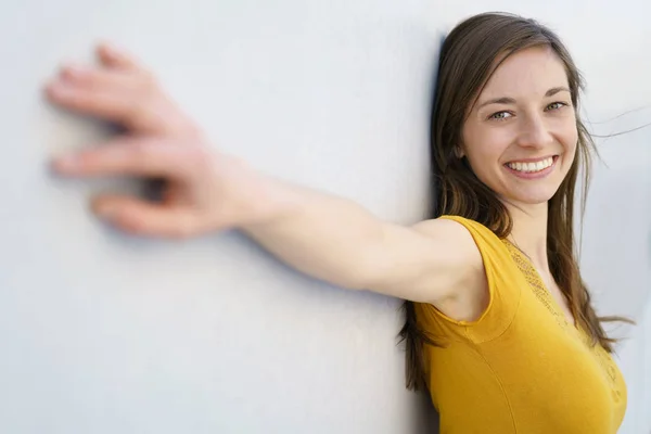 Szczęśliwa kobieta na białej ścianie z ramionami na bok — Zdjęcie stockowe