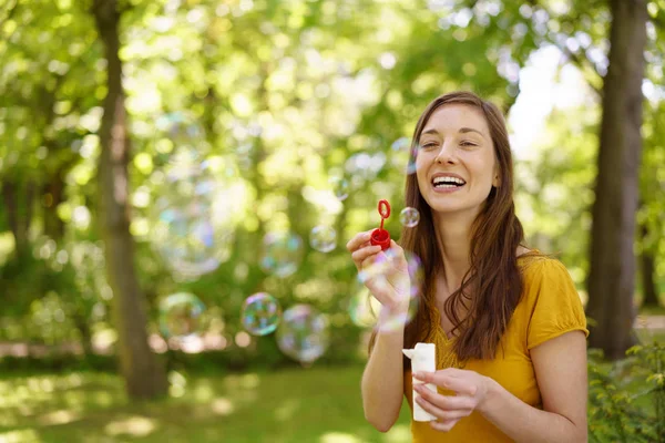 Směje se mladá žena foukání mýdlové bubliny — Stock fotografie