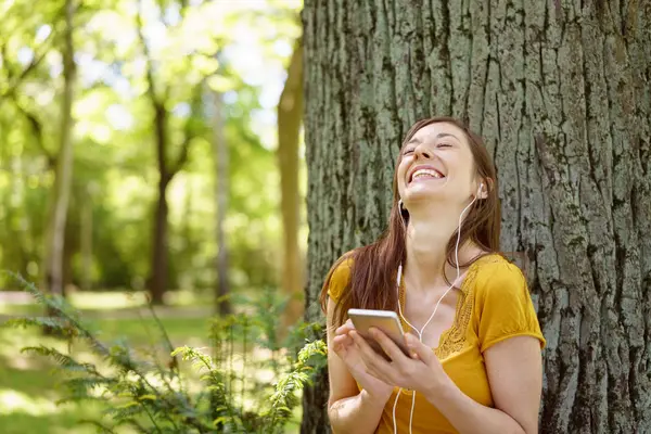 Joyeux jeune femme écoutant de la musique sur un mobile — Photo