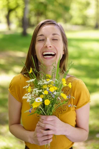 Laughing excited young woman holding flowers — Stock Photo, Image
