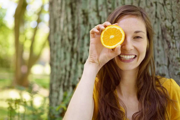 Игривая молодая женщина с апельсином в глазу — стоковое фото