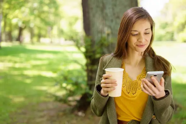 Молодая женщина отдыхает в парке с кофе — стоковое фото