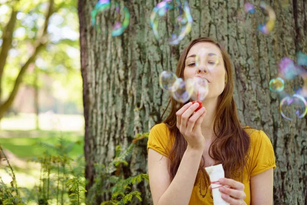 Mladá žena fouká duhové mýdlové bubliny — Stock fotografie