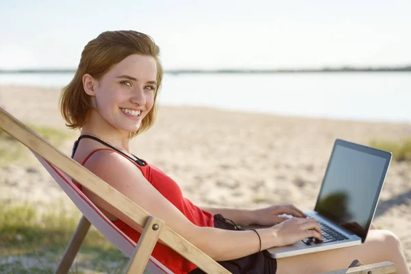 微笑在笔记本电脑上工作的年轻女子 — 图库照片