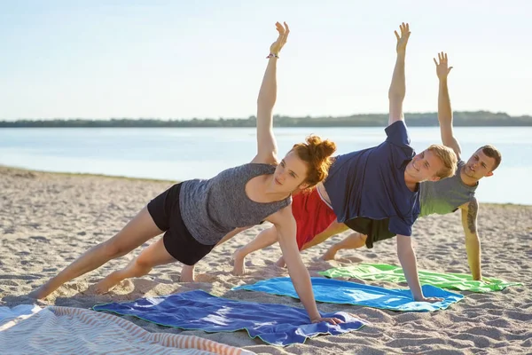 Three Young Friends Practicing Yoga Beach Stock Photo