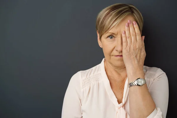 Senior woman covering left eye — Stock Photo, Image