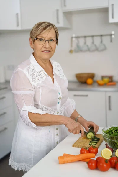 Starší žena připravuje salát v kuchyni — Stock fotografie