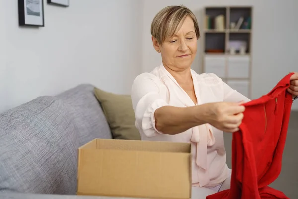 Старшая женщина достает одежду из коробки — стоковое фото
