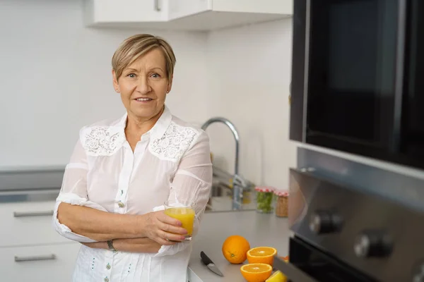 Senior Kobieta w kuchni z szklankę soku — Zdjęcie stockowe