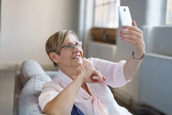 Femme âgée souriante prenant selfie avec smartphone — Photo