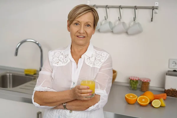 Seniorin hält Glas Orangensaft in der Hand — Stockfoto