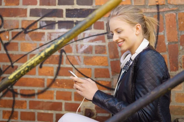 Junge Frau lächelt beim Benutzen eines Mobiltelefons — Stockfoto