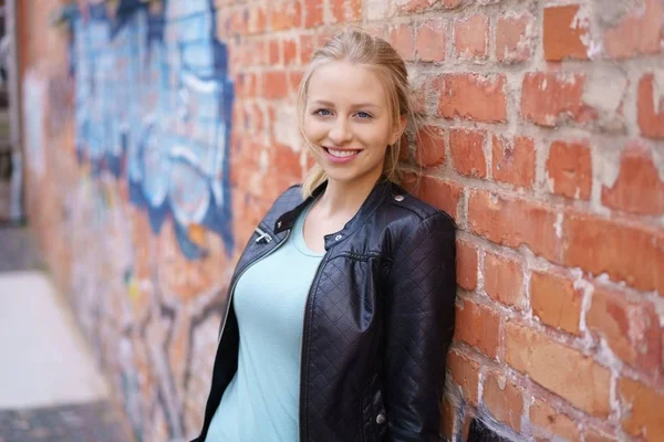 Mujer joven y bonita apoyada en una pared de ladrillo — Foto de Stock