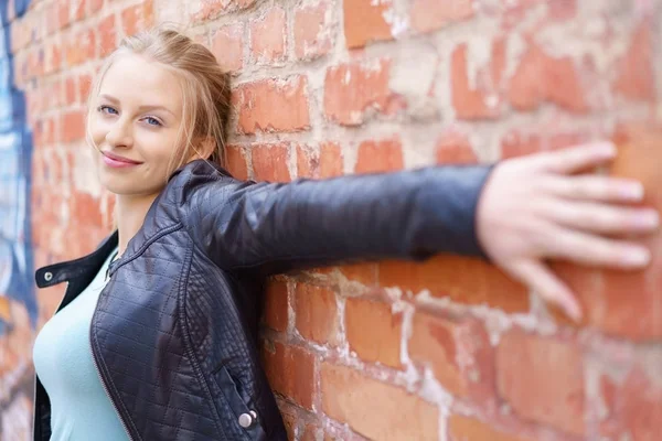 Jeune femme étirant le long d'un mur de briques — Photo