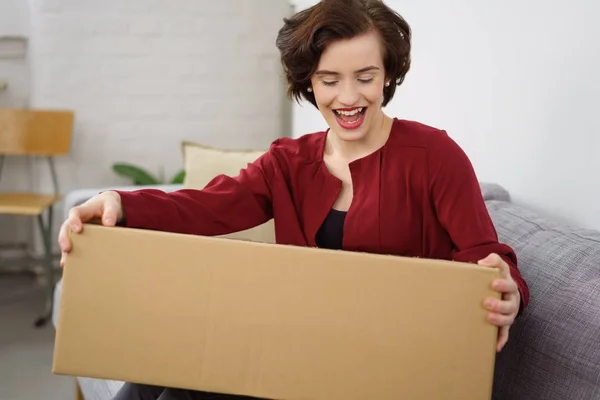 Young cheerful woman sitting with cardboard box — Stock Photo, Image