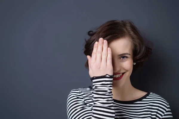 Hübsche lächelnde Frau, die ein Auge bedeckt — Stockfoto