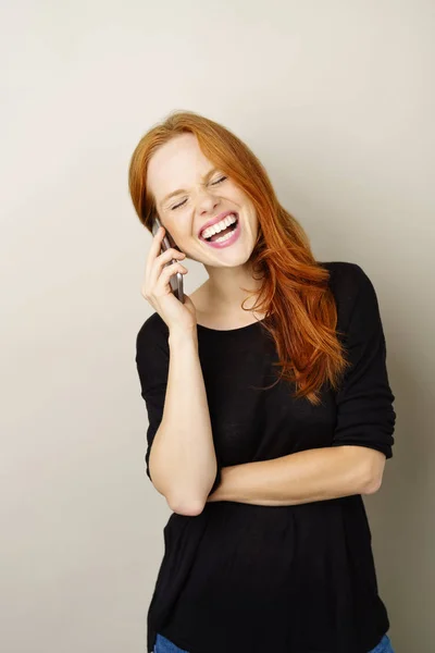 Mujer joven riendo mientras escucha una llamada —  Fotos de Stock