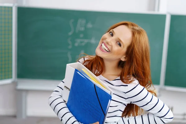 Giovane donna sorridente che tiene i file in classe — Foto Stock