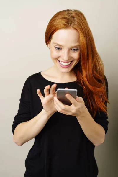 Glücklich lächelnde Frau, die auf ihrem Handy SMS schreibt — Stockfoto