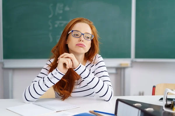 Gelangweilte junge Frau sitzt im Klassenzimmer am Schreibtisch — Stockfoto