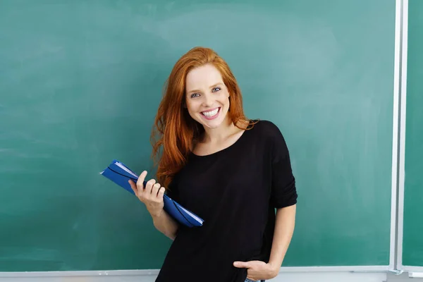 Jonge lachende vrouw permanent tegen blackboard — Stockfoto