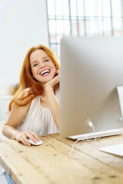 Молодая веселая женщина, работающая за компьютером — стоковое фото