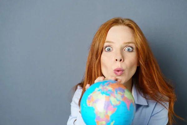 Mulher jovem espantada segurando um globo mundial — Fotografia de Stock