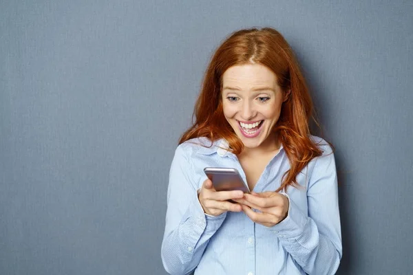 Jeune femme enthousiaste gingembre utilisant le téléphone mobile — Photo