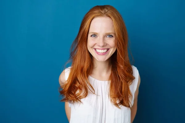 Młoda kobieta uśmiechający się niebieskim tle — Zdjęcie stockowe