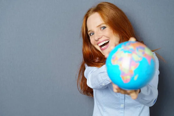 Laughing vivacious woman holding out a globe — Stock Photo, Image