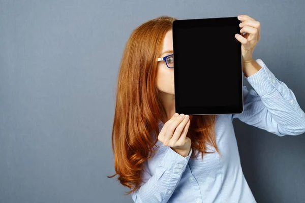 Ung ingefära kvinna gömmer sig bakom digital tablett — Stockfoto