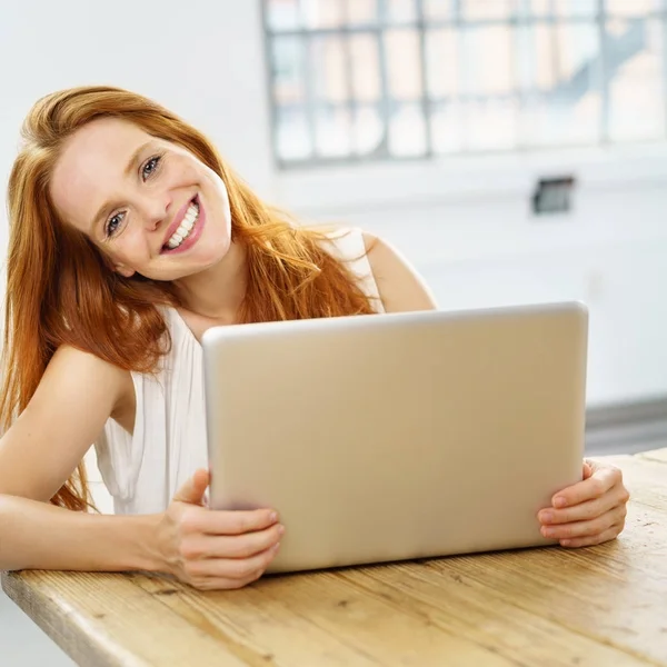 Молода усміхнена руда жінка використовує ноутбук — стокове фото