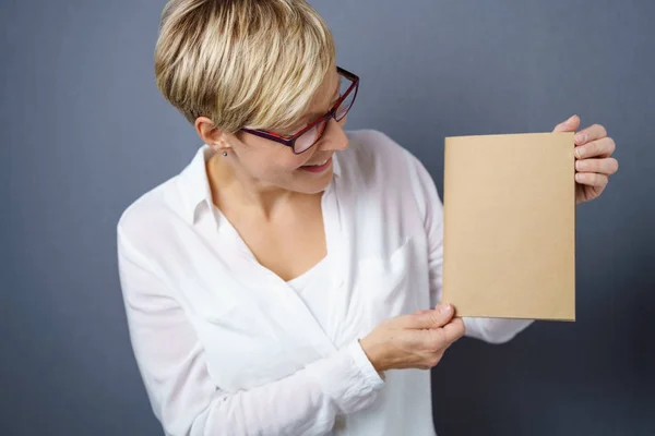 Uśmiechnięta kobieta, patrząc na brązowy kawałek papieru — Zdjęcie stockowe