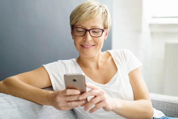 Avslappnad ung kvinna läsa ett textmeddelande — Stockfoto
