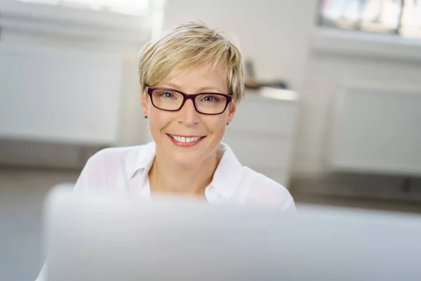 Jeune femme travaillant à un ordinateur dans un bureau — Photo