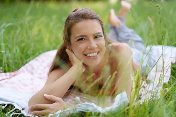 Mutlu genç kadın yeşil çimenlerin üzerinde rahatlatıcı — Stok fotoğraf
